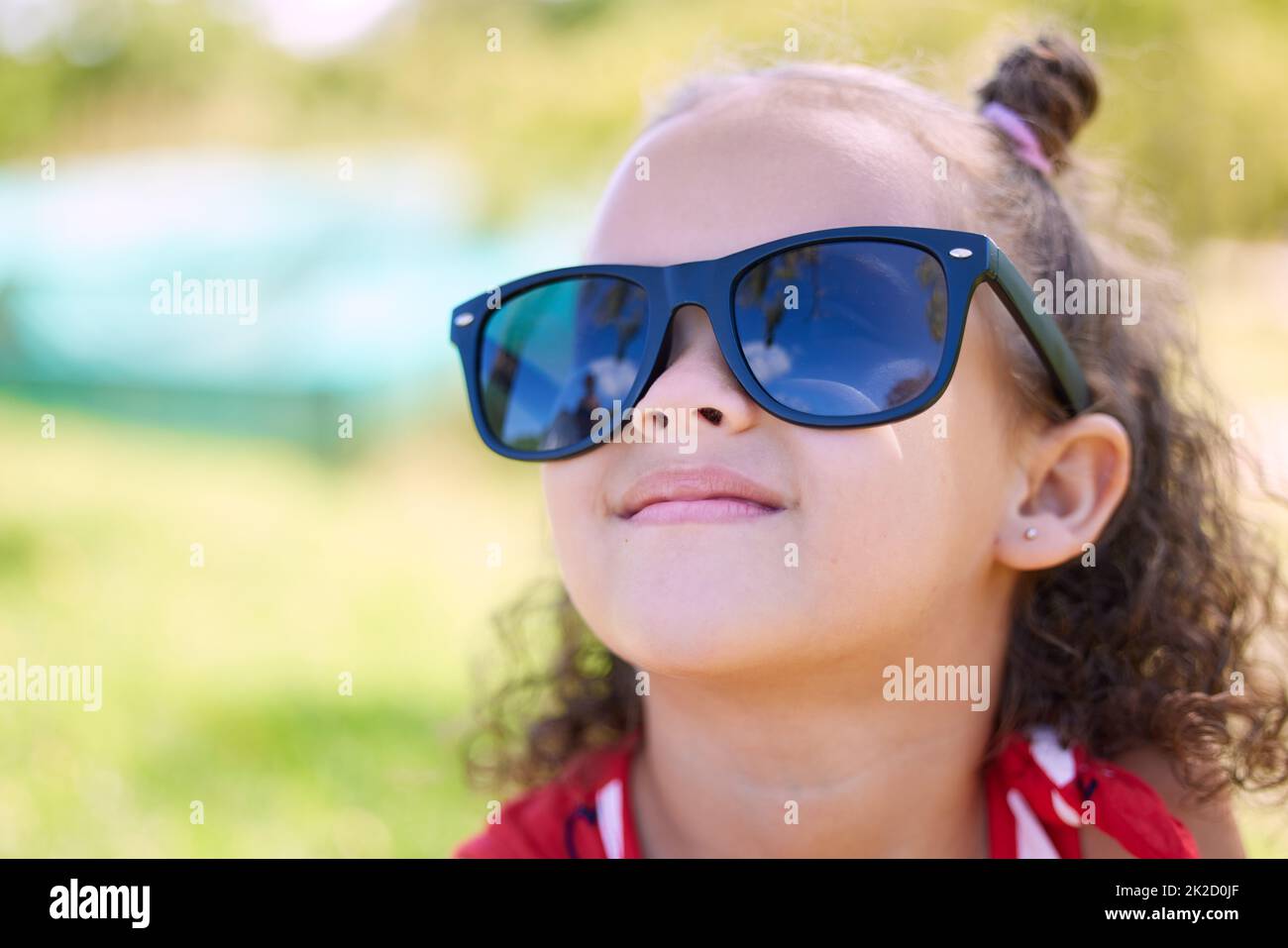 Everyone loves sunny days. Shot of an adorable little girl wearing sunglasses while at the park. Stock Photo