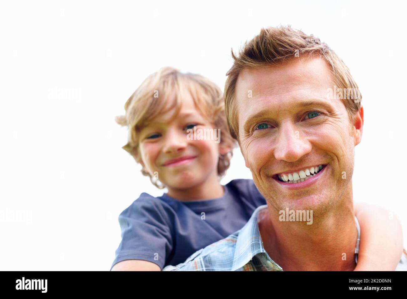 Happy mature man piggybacking his son against sky. Closeup portrait of a happy mature man piggybacking his son against sky. Stock Photo