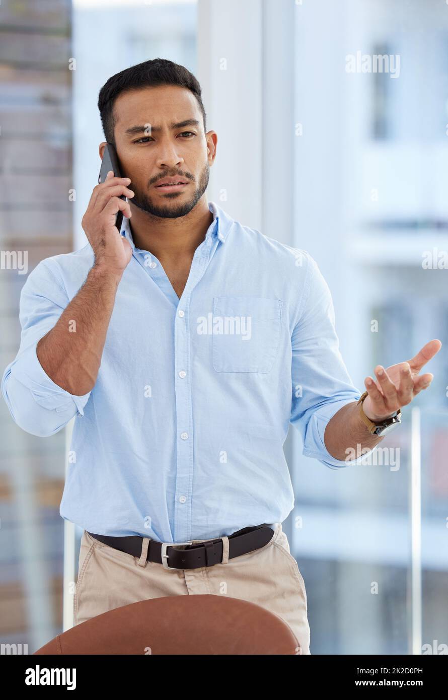 How much longer do I have to wait for an update. Shot of a young businessman talking on a cellphone in an office. Stock Photo