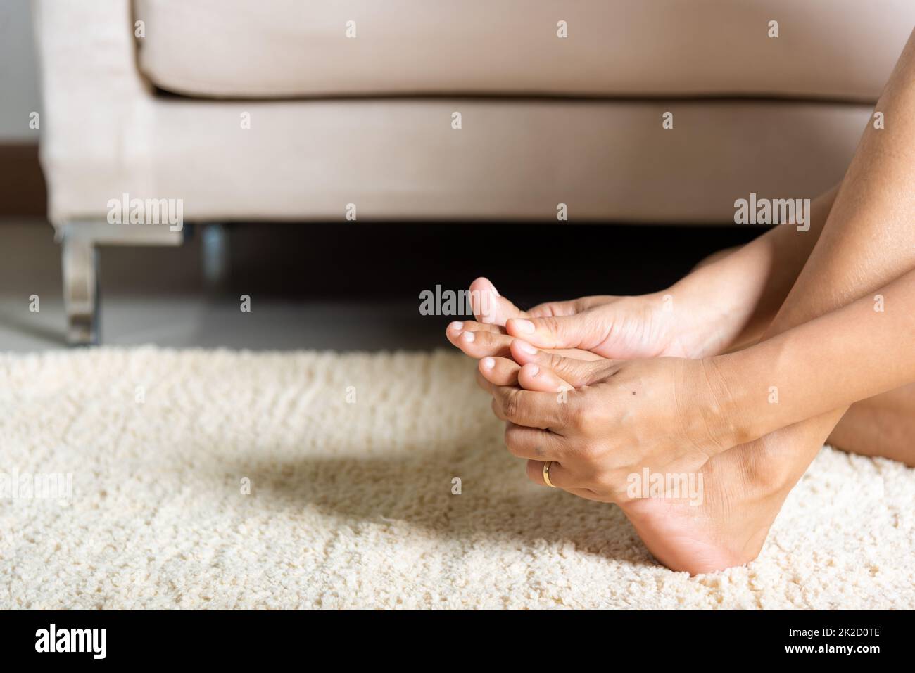 Asian woman holds her toe injury feeling pain her foot at home Stock Photo