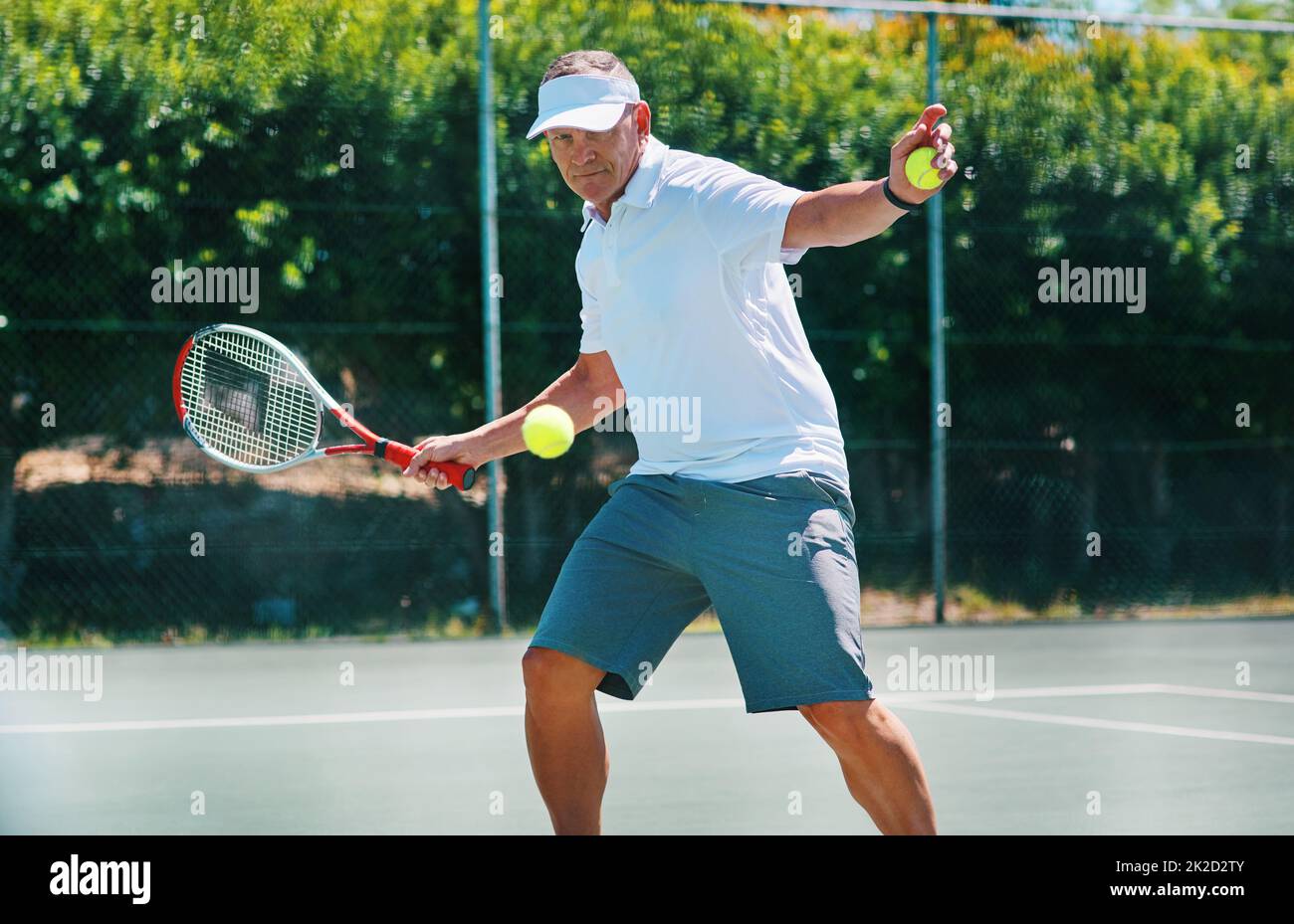 Staying healthy is a lifestyle. Cropped shot of a handsome mature man playing tennis alone on a court during the day. Stock Photo