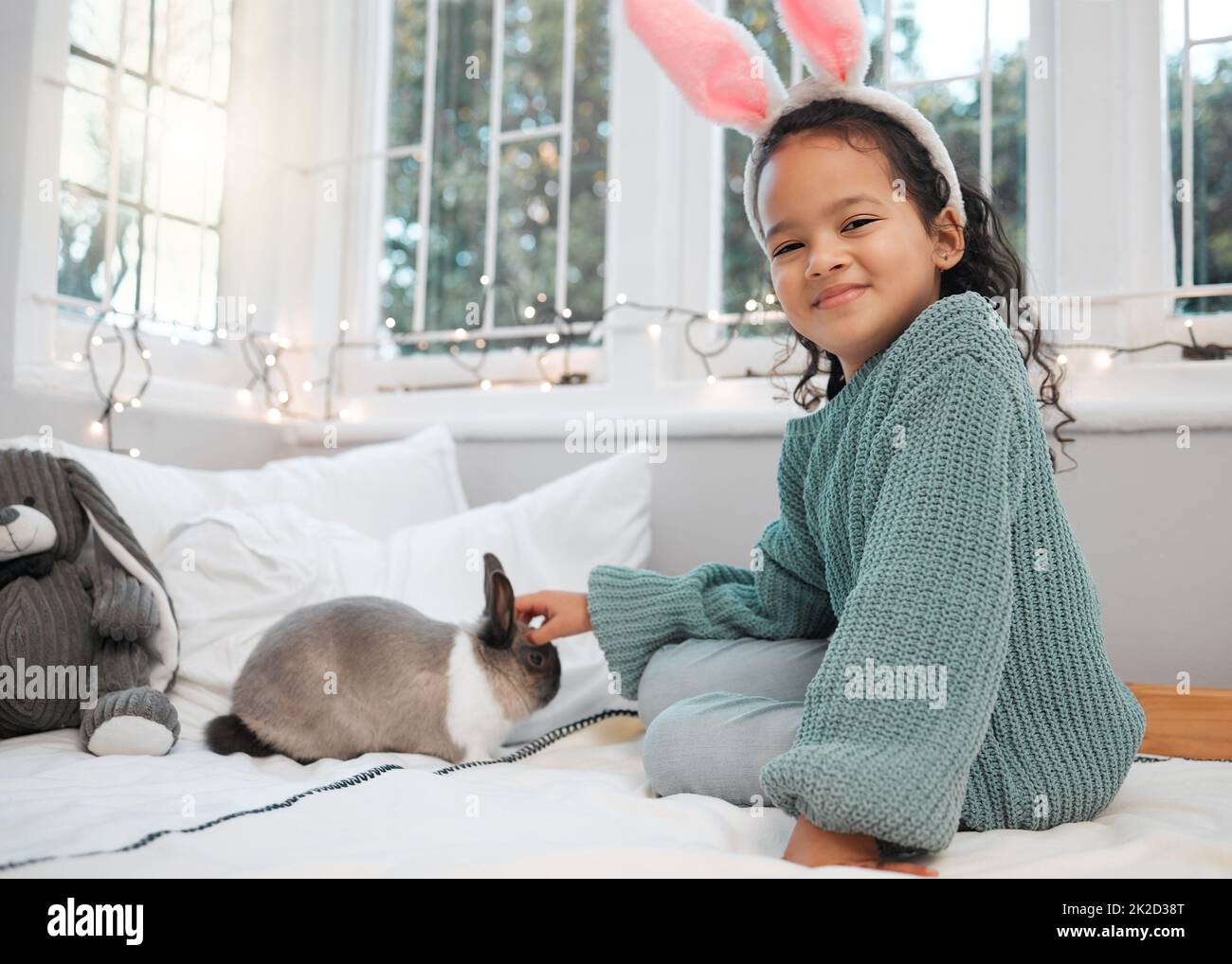 Look, were matching. Shot of an adorable little girl sitting on her bed and bonding with her pet rabbit at home. Stock Photo