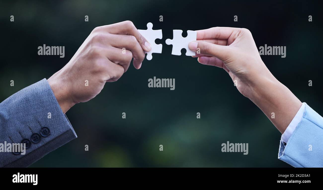 Combining two brilliant business ideas. Cropped shot of two unrecognisable businesspeople standing together and holding puzzle pieces. Stock Photo