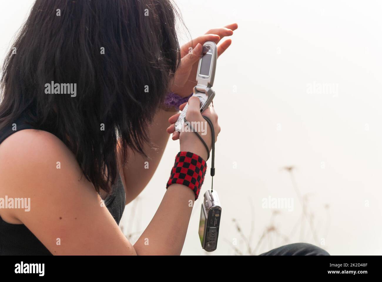 Punk emo girl, young adult with black hair using mobile phone Stock Photo