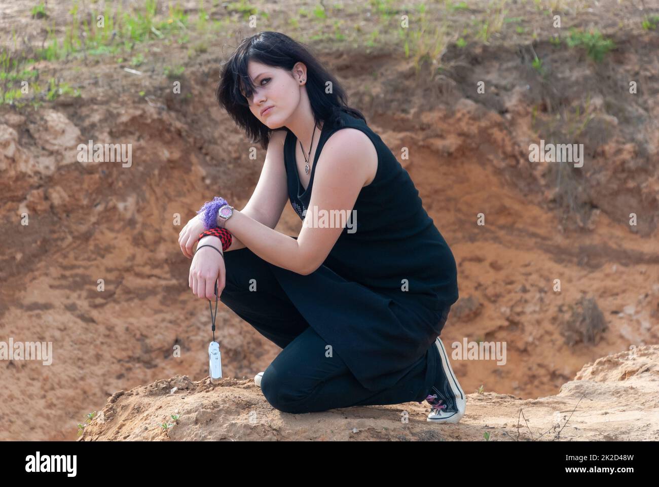 Punk emo girl, young adult with black hair, kneeling, looking at camera Stock Photo