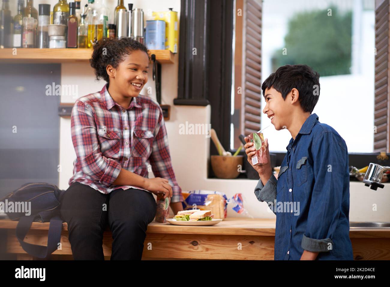 Having a tasty nibble after school. Shot of two young teenagers enjoying a snack together in the kitchen. Stock Photo