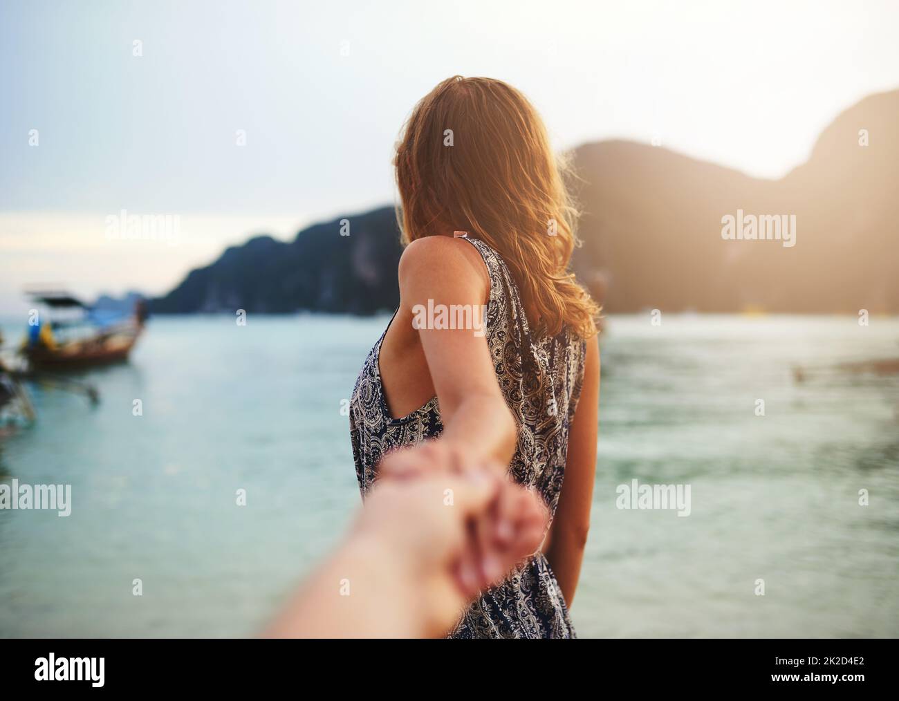 Follow me to paradise. Shot of a young woman leading someone by the hand at the beach. Stock Photo