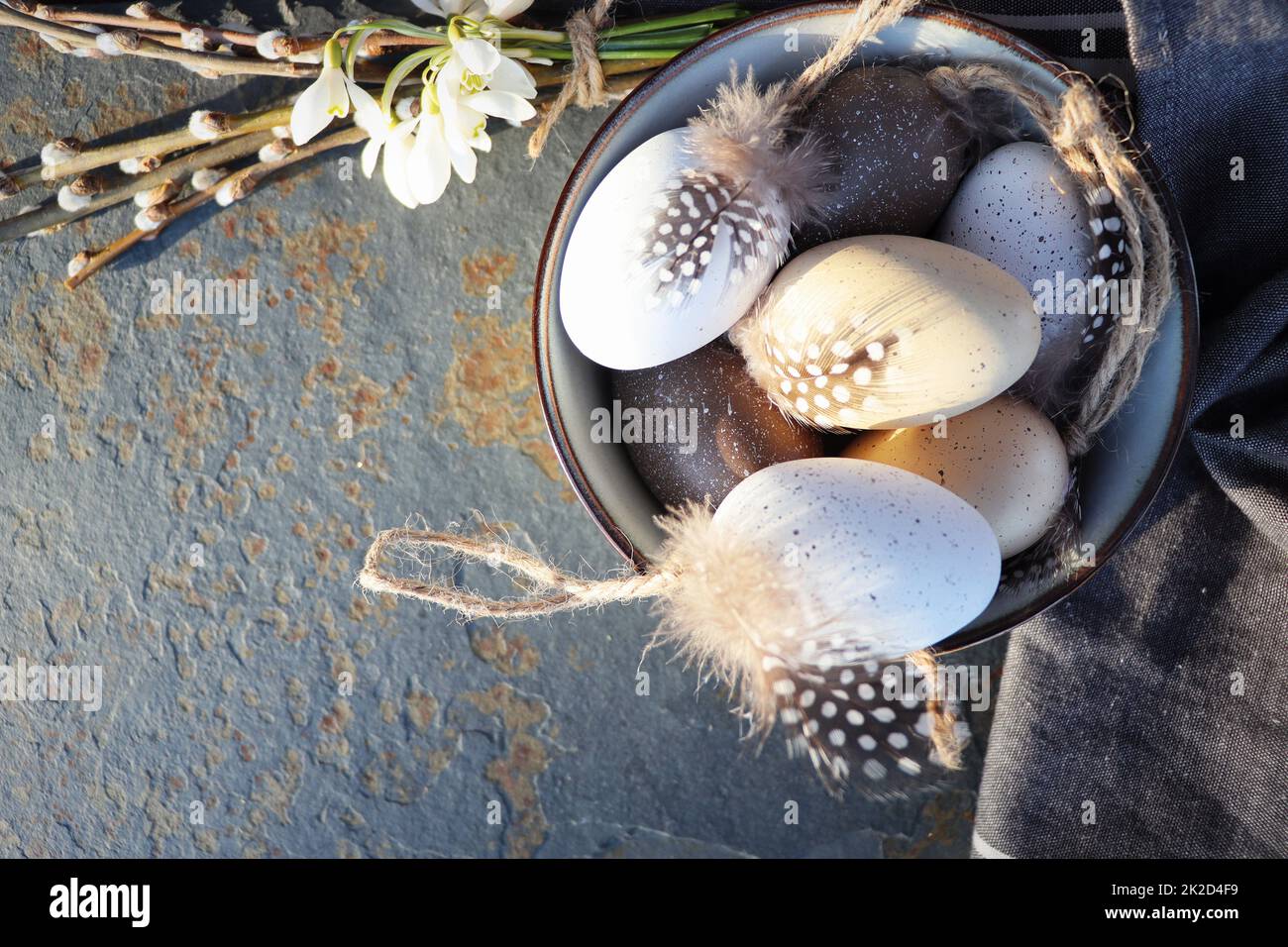 Happy Easter. Quail egg in a ceramic bowl and Spring flower decoration, stone gray table background, top view, copy space. Greeting card template Stock Photo