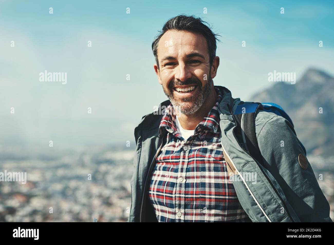 Smiles are forms of happiness found right under our noses. Portrait of a middle aged man smiling in front of a mountain landscape. Stock Photo