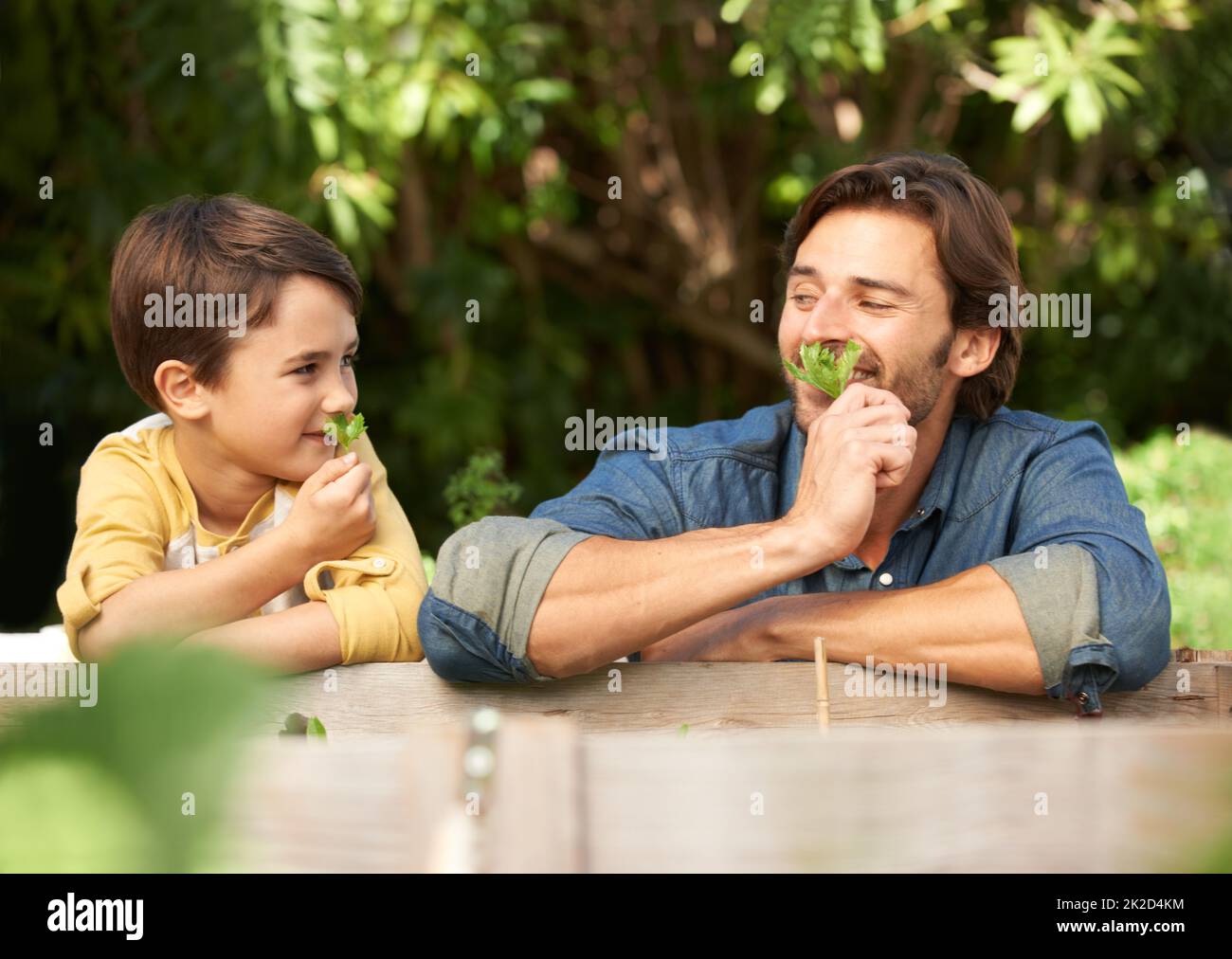 Mmm... smell that. Shot of a father and his son spending time together in the garden. Stock Photo