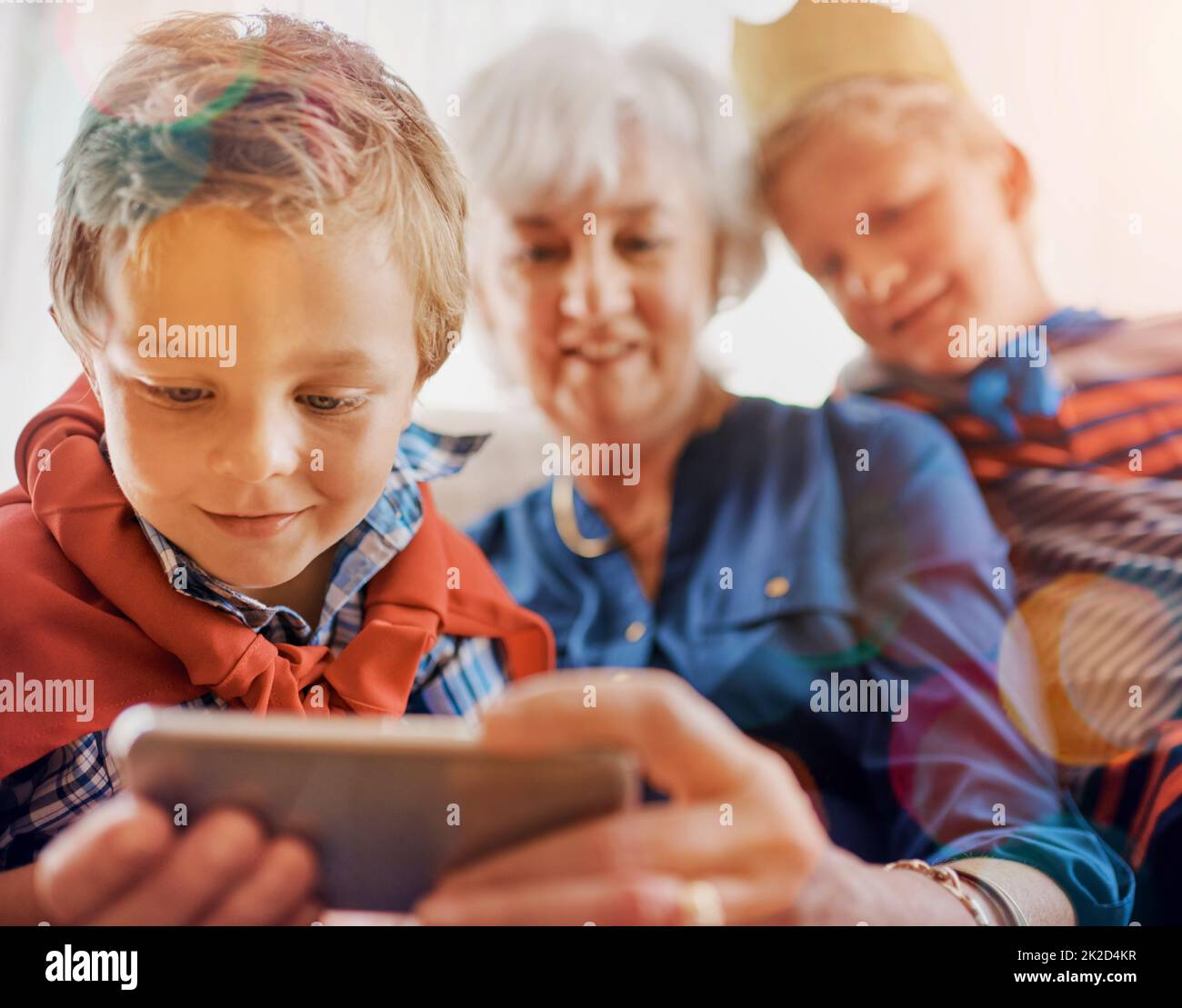 Grannys cellphone is his favorite toy. Shot of a senior woman spending time wither her grandsons. Stock Photo