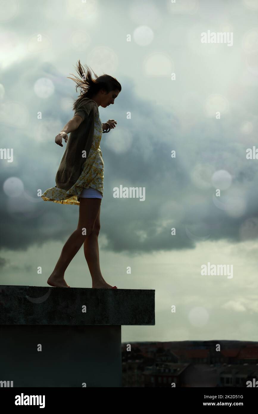 Living with abandon. Young woman walking on a rooftop with her arms outstretched. Stock Photo