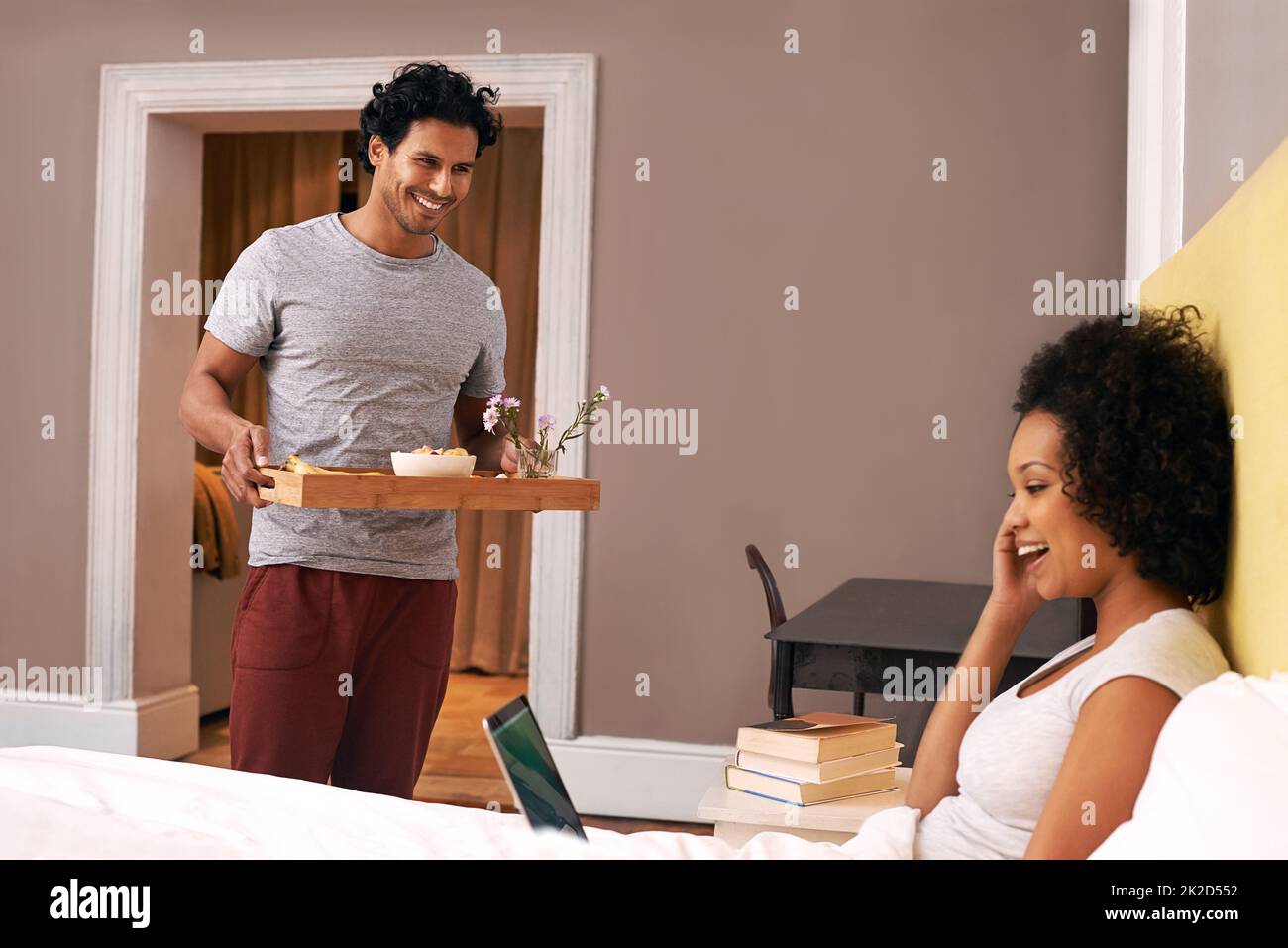 Surprising her with breakfast. A young man bringing his girlfriend breakfast in bed. Stock Photo