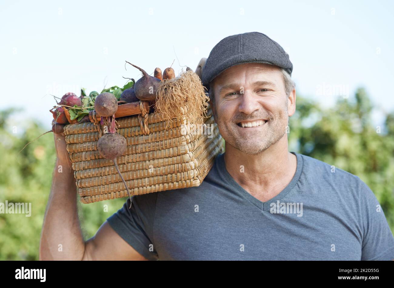Proud of his produce. A smiling mature farmer holding a basket of fresh produce. Stock Photo