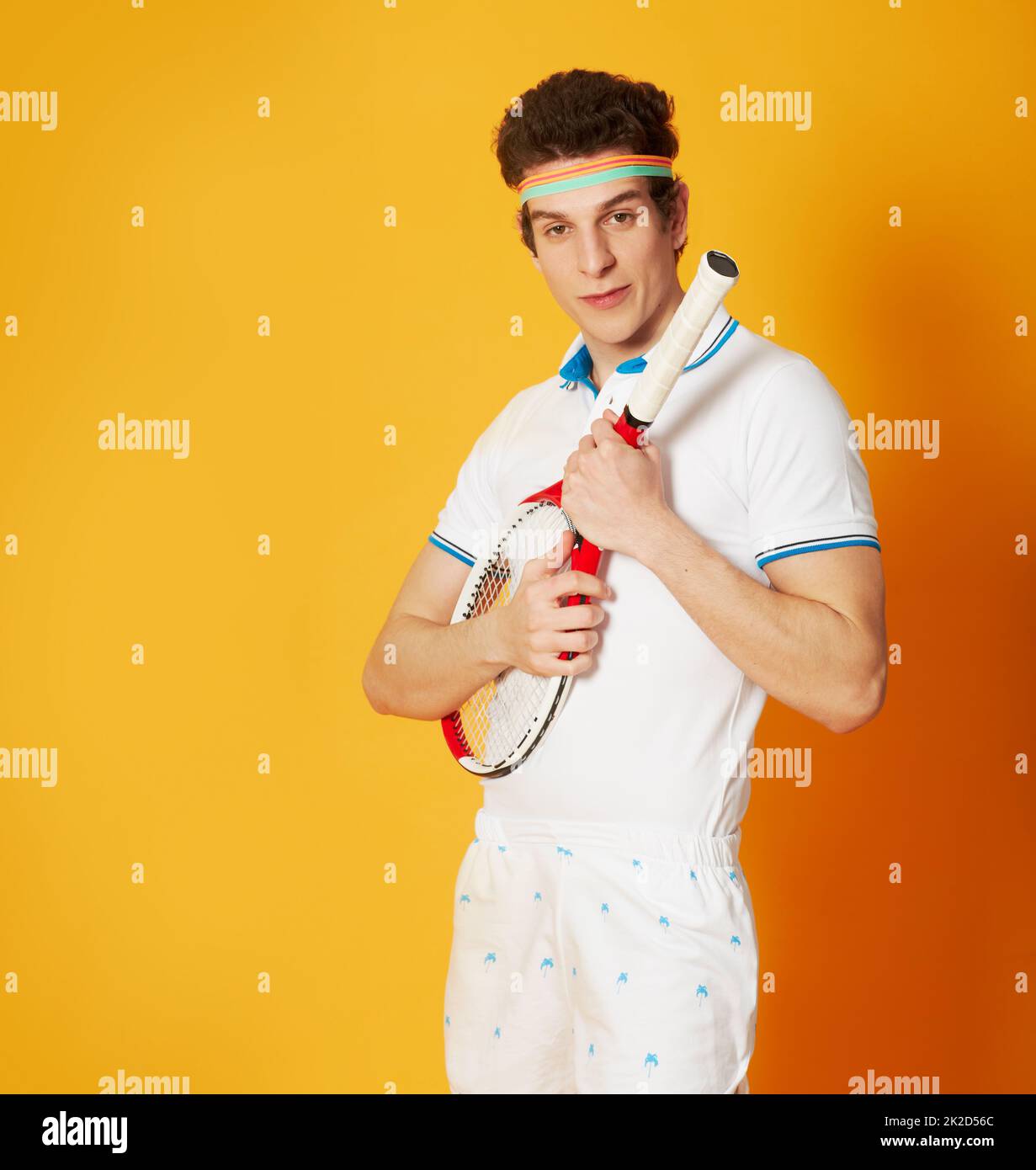 How do you hold this again. A young man in a retro tennis outfit holding his racket like a quitar. Stock Photo