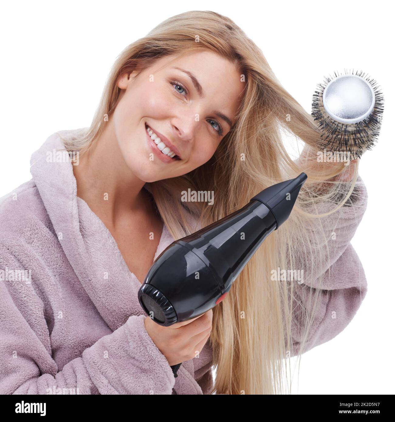 Making beautiful curls.... Studio shot of a woman in a robe blow drying her hair. Stock Photo