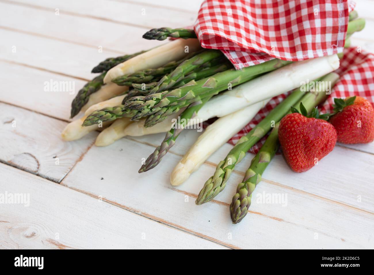Asparagus with strawberries on white wood Stock Photo