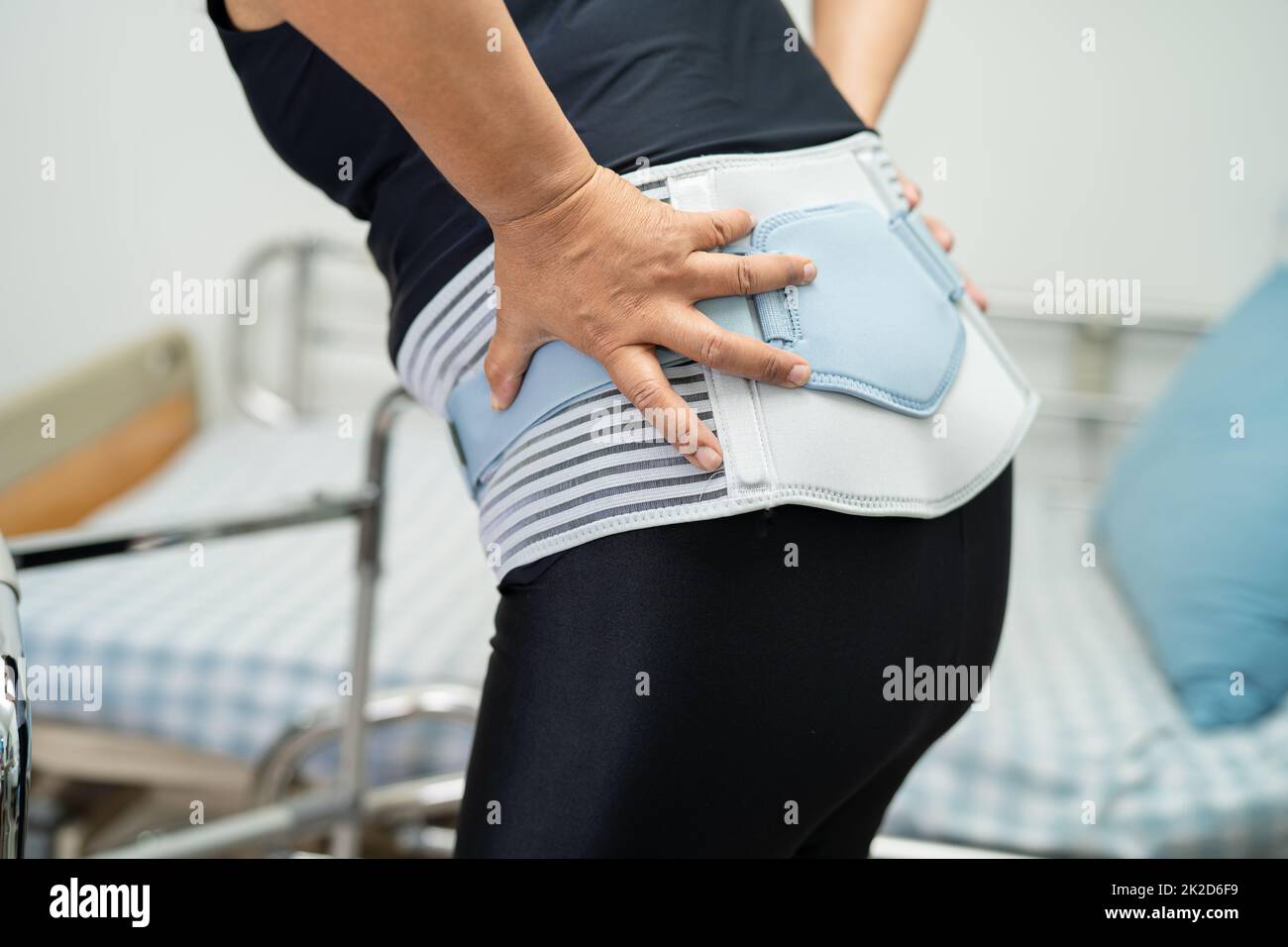 Asian lady patient wearing back pain support belt for orthopedic lumbar ...