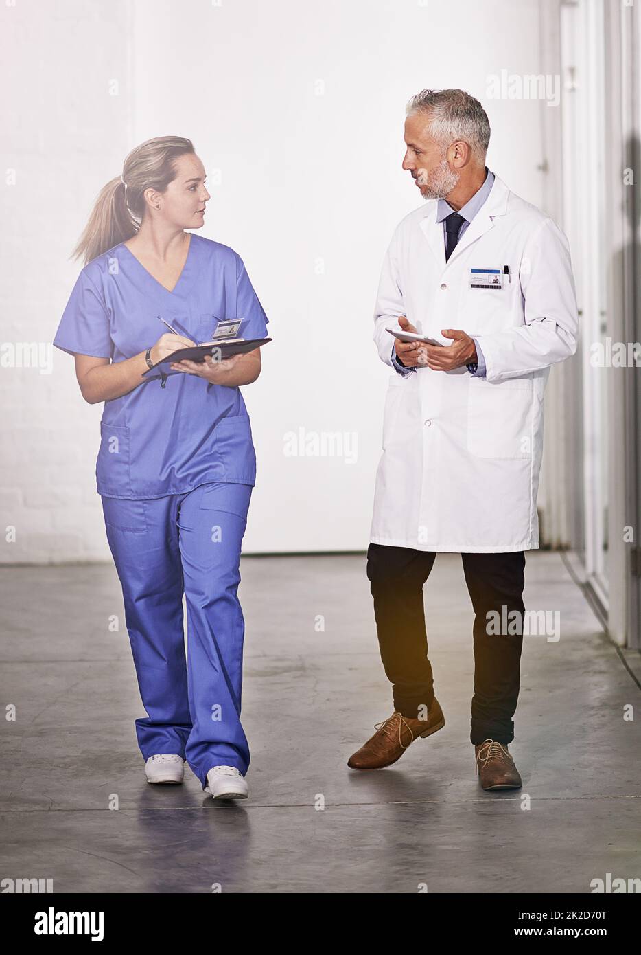 Passing on some of his expertise. Full length shot of a mature doctor teaching a female intern in the hospital corridor. Stock Photo