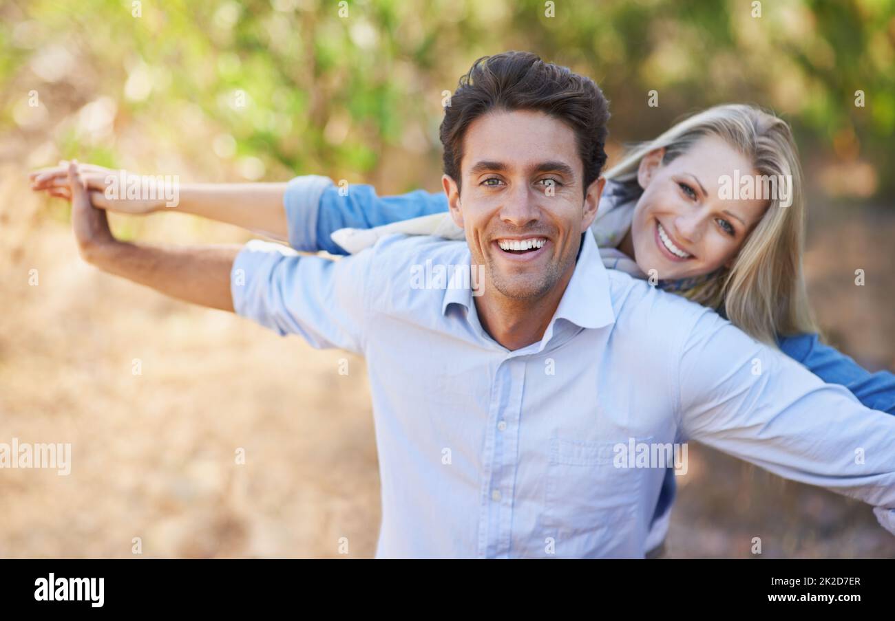 Playful and filled with love. A loving young couple standing together outdoors with their arms outstretched. Stock Photo