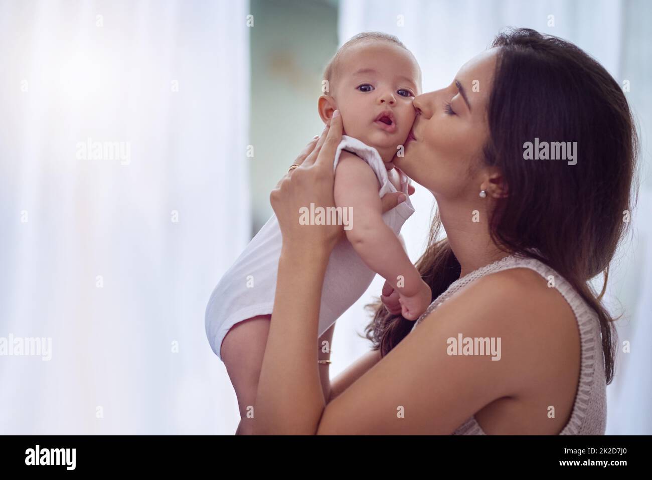 I know, these cheeks are hard to resist. Shot of a young woman bonding with her baby boy at home. Stock Photo