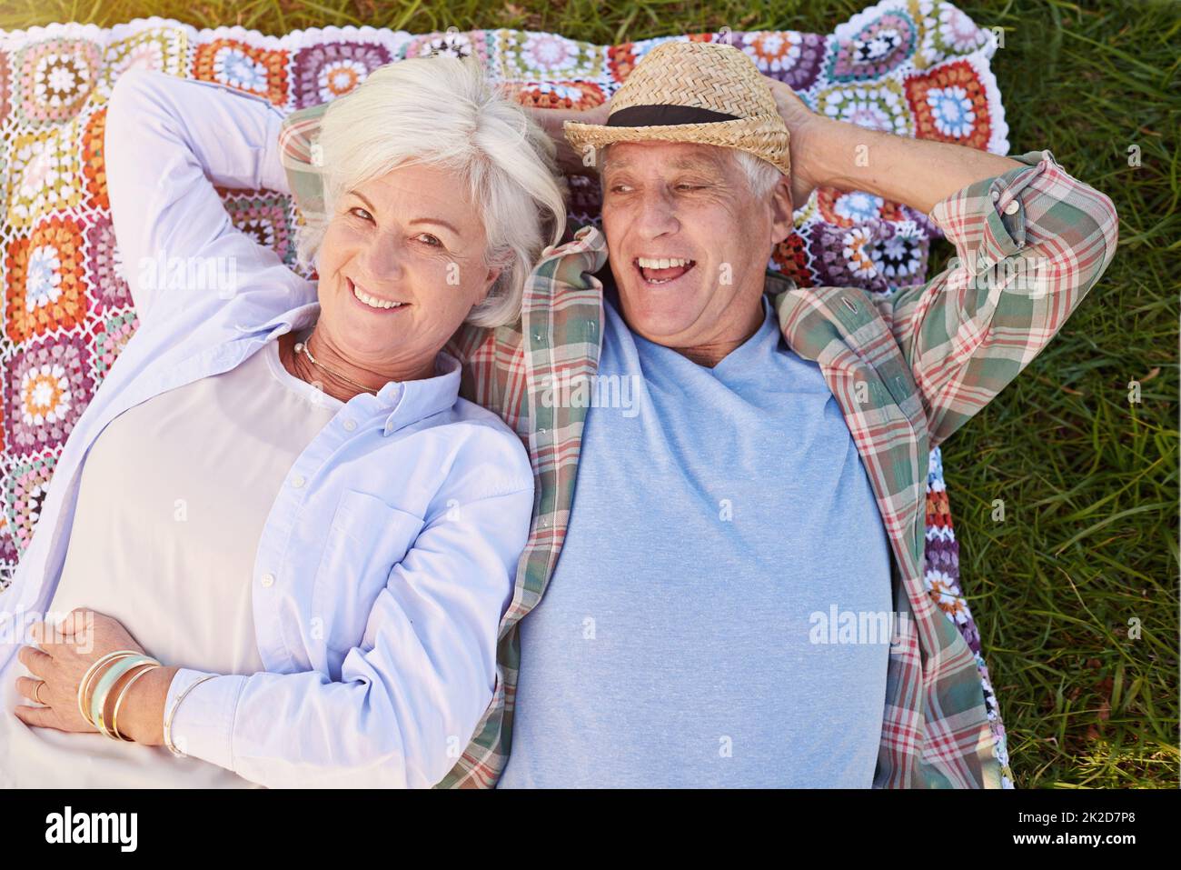 This is one relaxing retirement. Portrait of a happy senior couple relaxing together on the lawn. Stock Photo