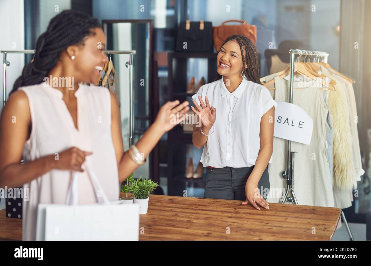 Thank you for shopping with us. Cropped shot of a cashier and a customer waving goodbye to each other. Stock Photo