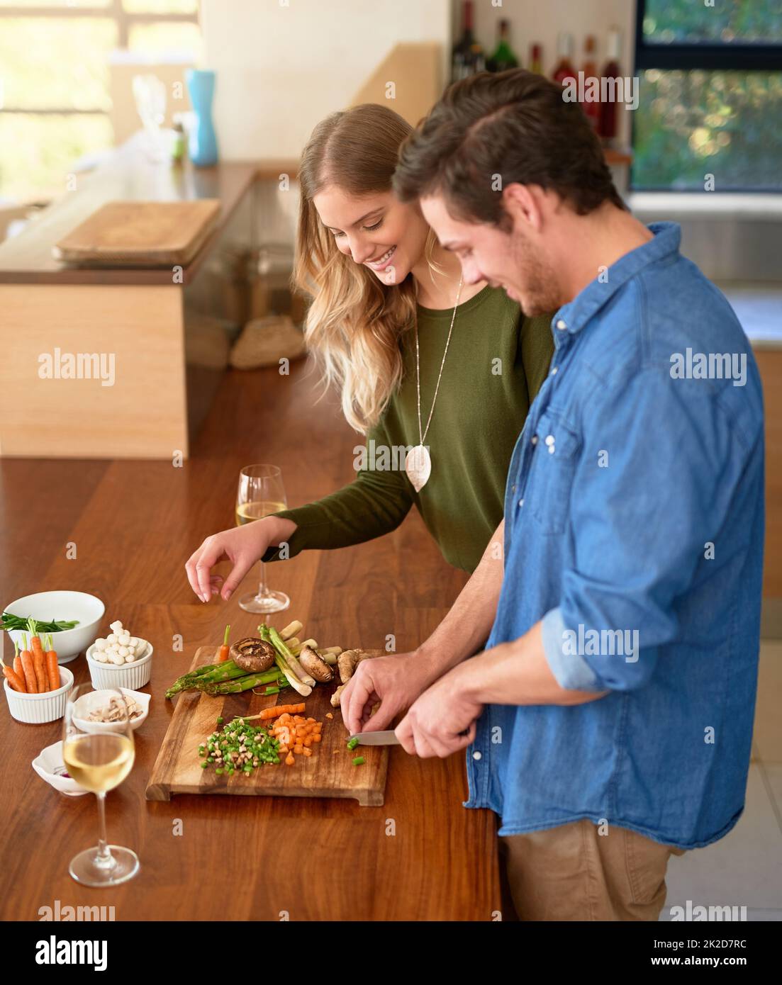 Making the perfect meal together. Shot of a smiling young couple standing at their kitchen counter chopping up ingredients together for dinner. Stock Photo