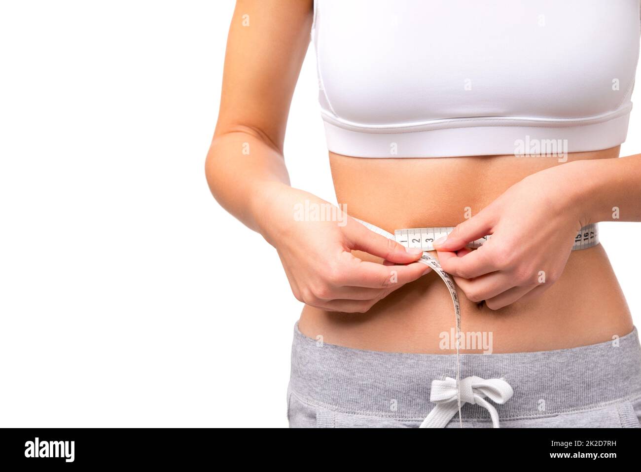 Measuring progress. Closeup of a fit womans waist while she is measuring it with tape. Stock Photo