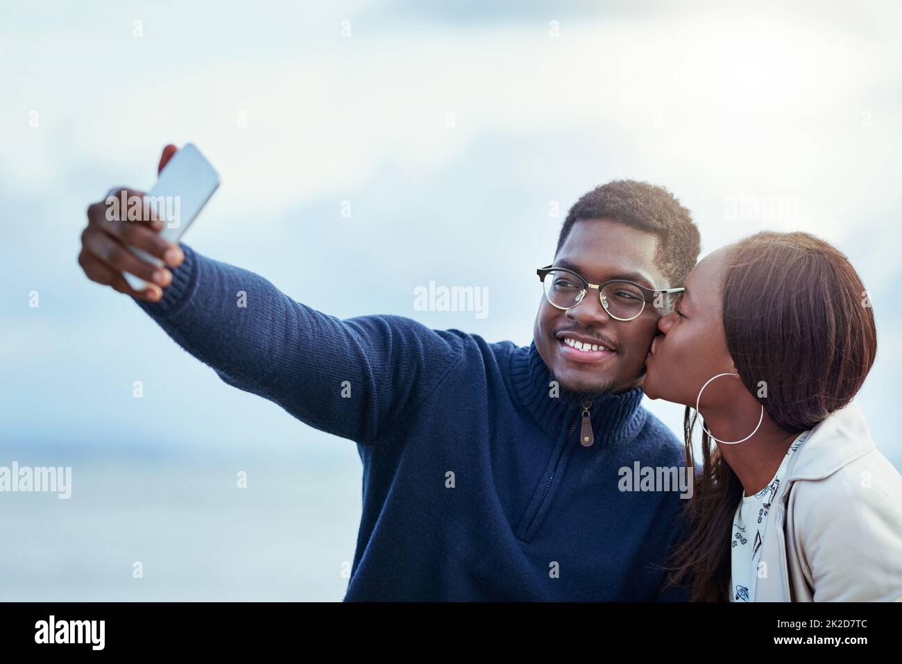 Theyre definitely madly in love. Shot of an affectionate young couple taking selfies together outdoors. Stock Photo
