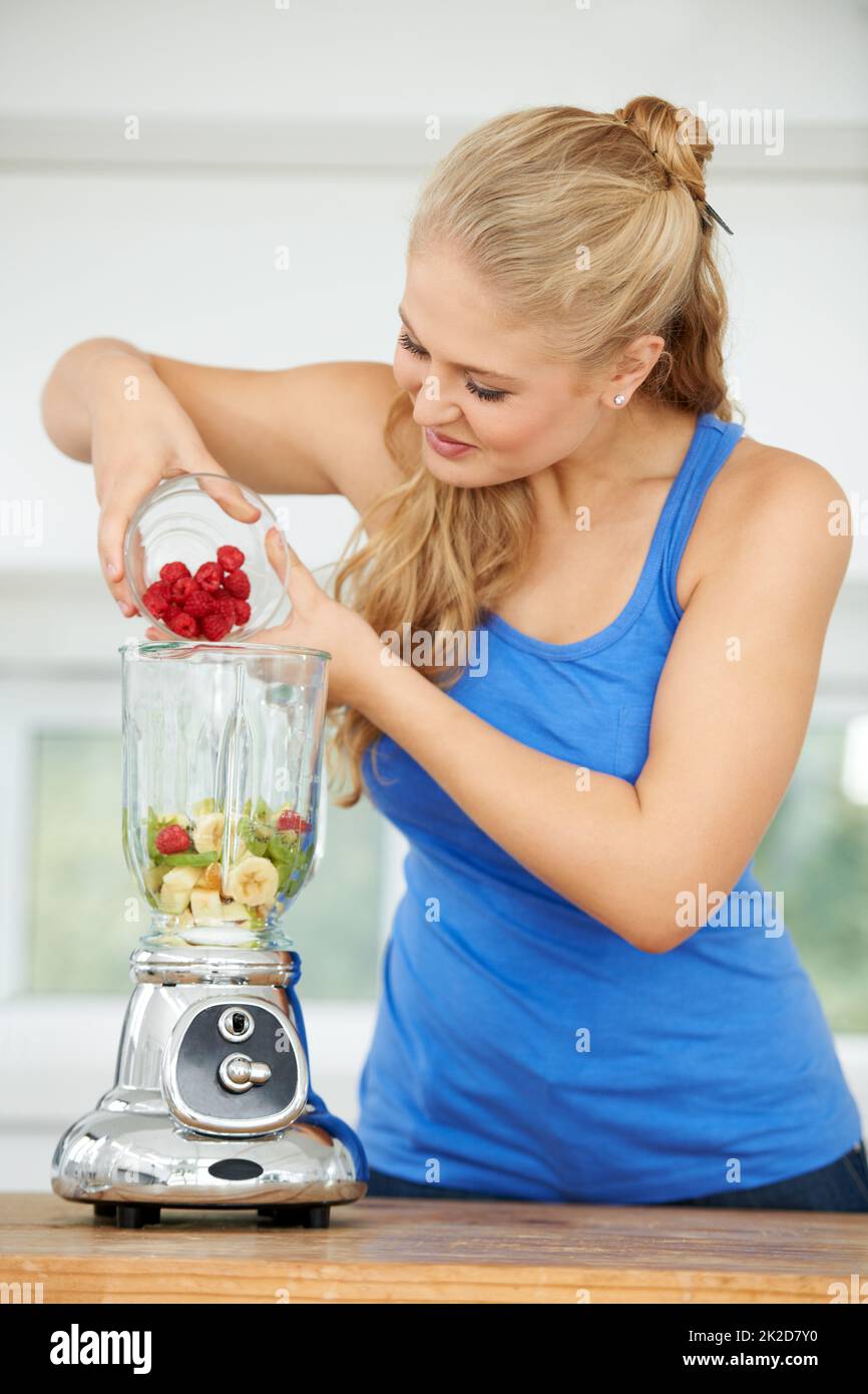 Getting ready to blend the perfect smoothie. Attractive young woman making a fruit smoothie. Stock Photo