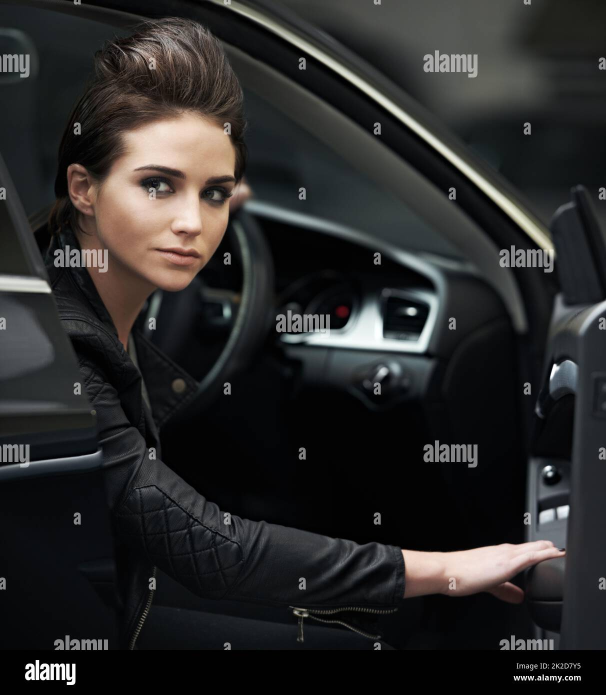 Stylish chic in her luxury car. A leatherclad woman sitting