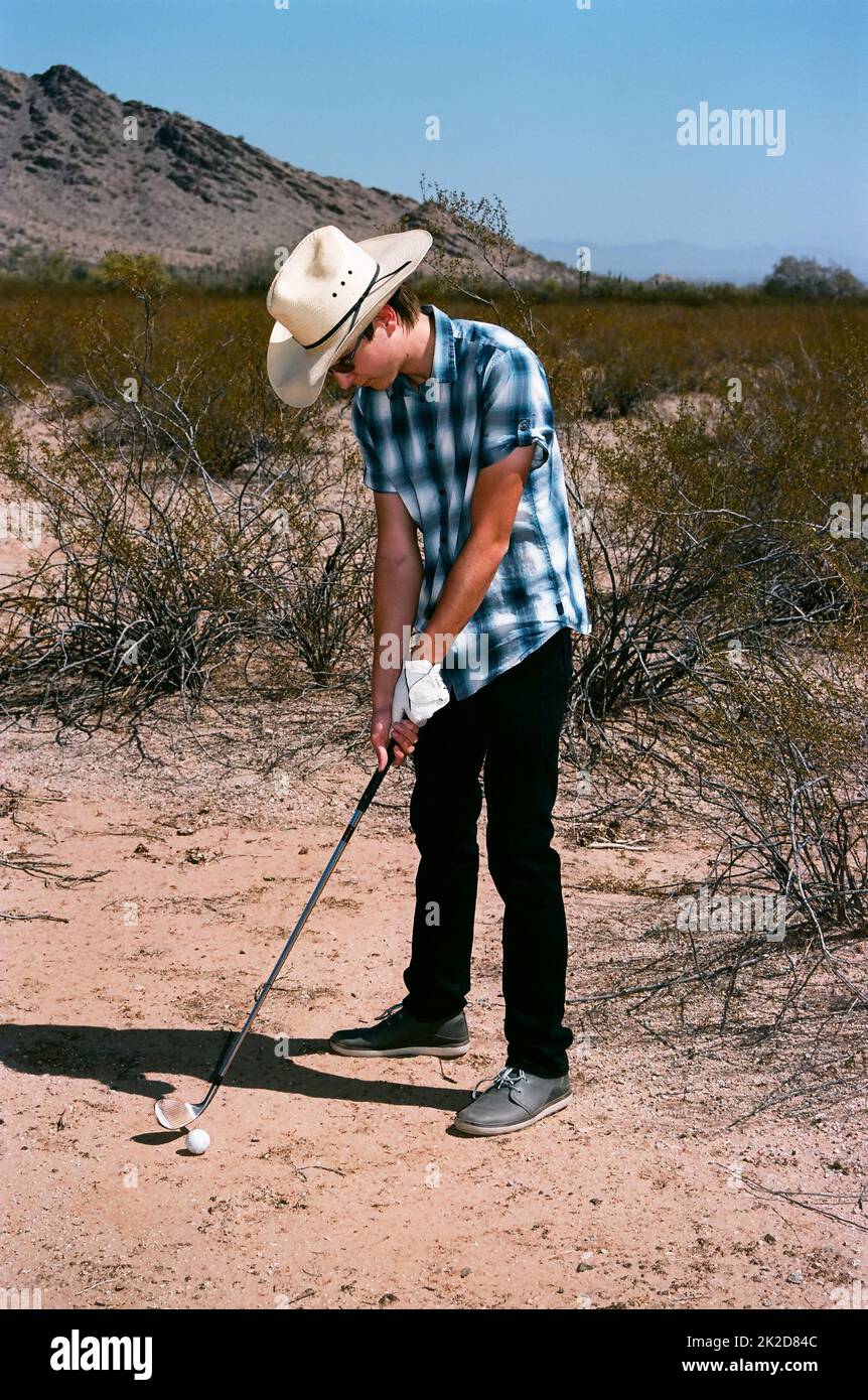Young boy golfing in the desert Stock Photo