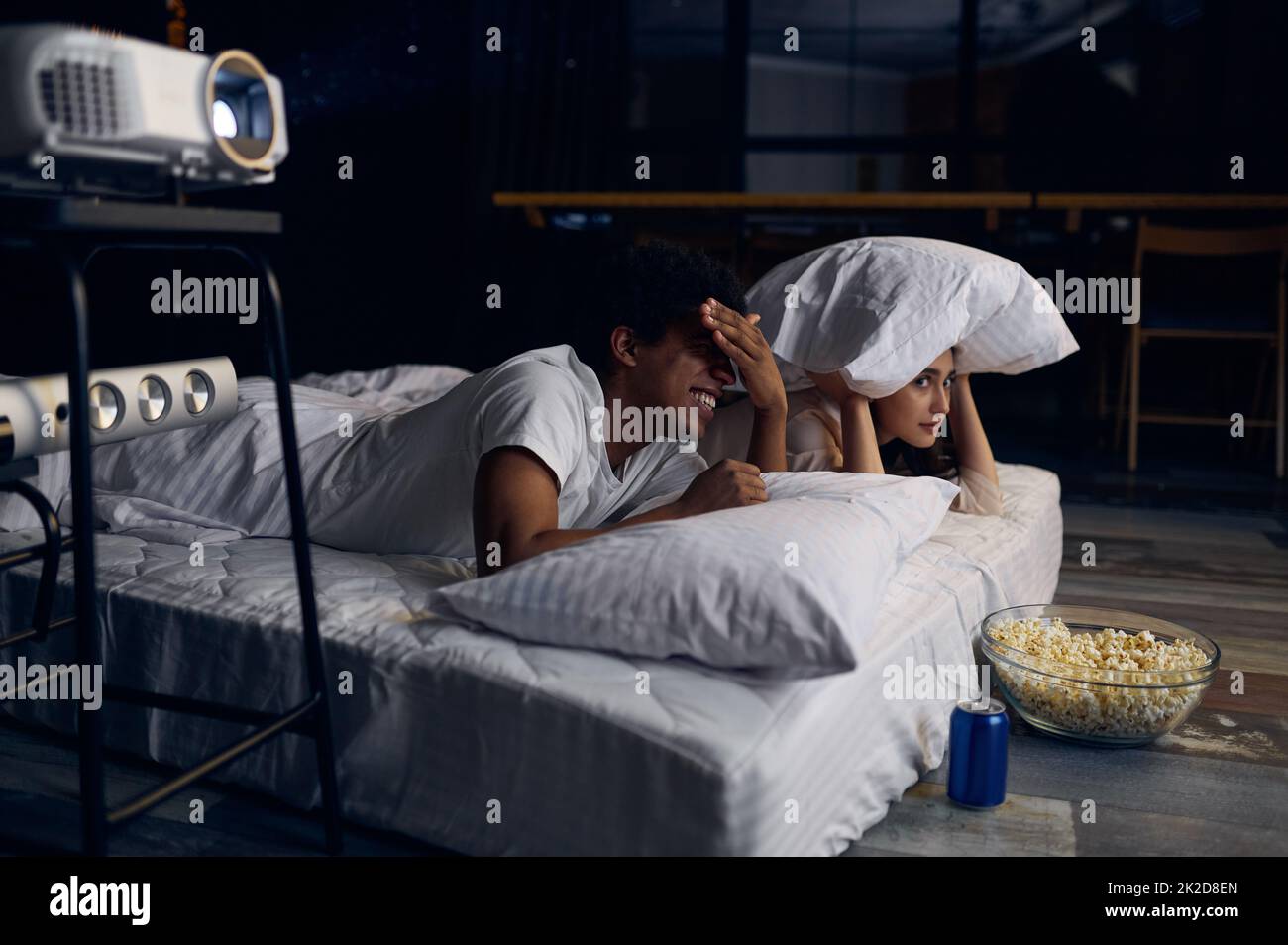 Funny couple watching horror film in bedroom Stock Photo