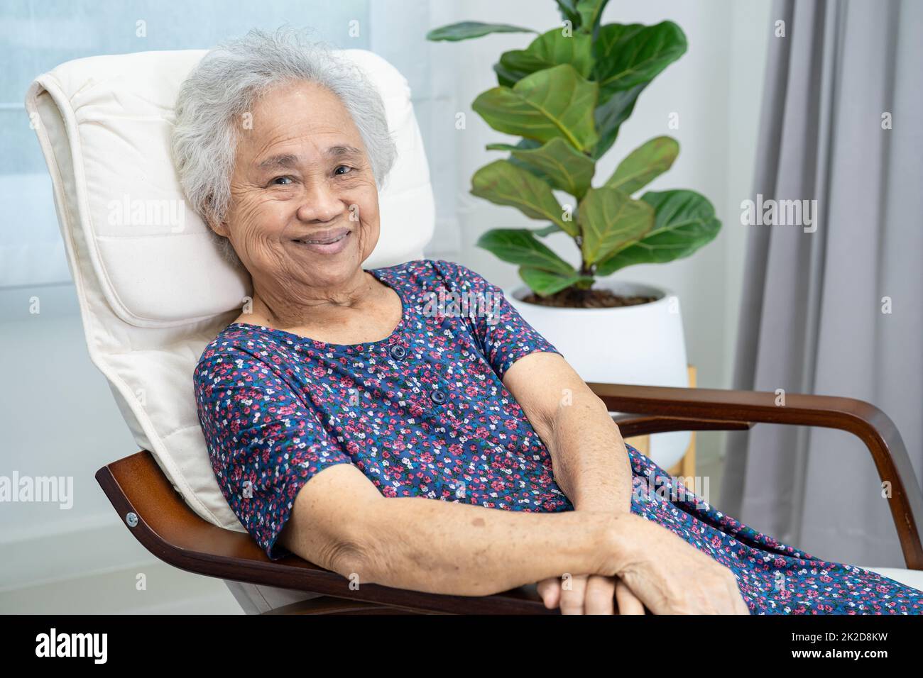 Asian elderly woman sitting and relaxing with happy in rocking chair at room in home. Stock Photo
