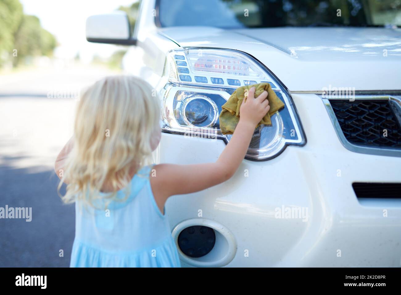 Cleaning the car. Shot of a young girl washing a car outside Stock