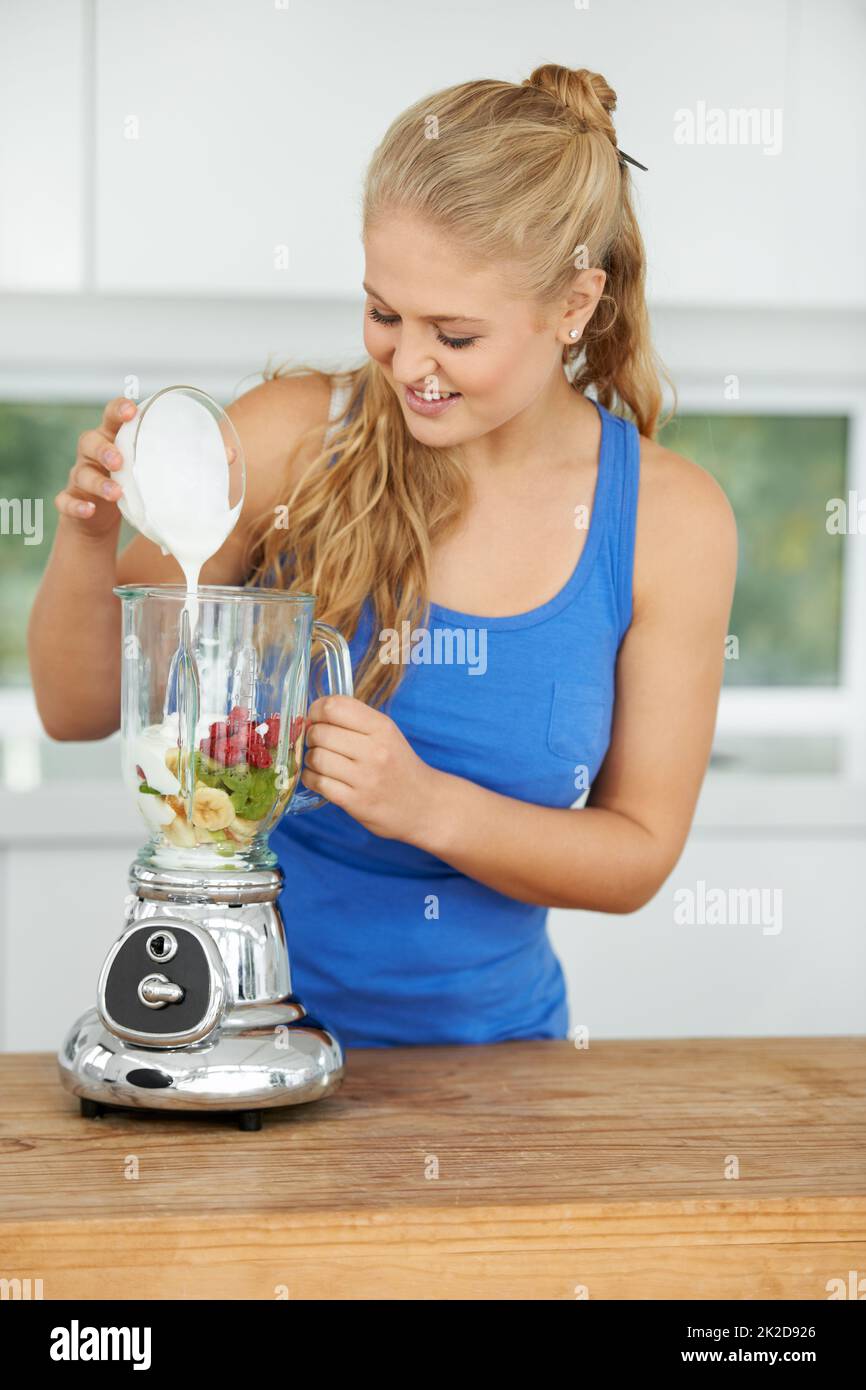 Creating a fantastic smoothie. Attractive young woman making a fruit smoothie Stock Photo Alamy