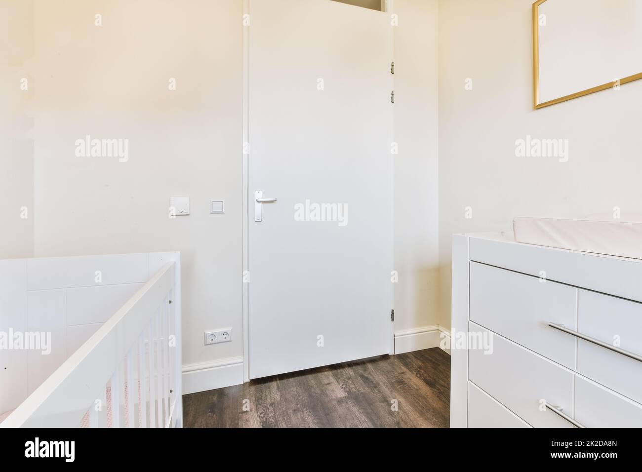 Interior of white room with baby crib near window with blue chest of