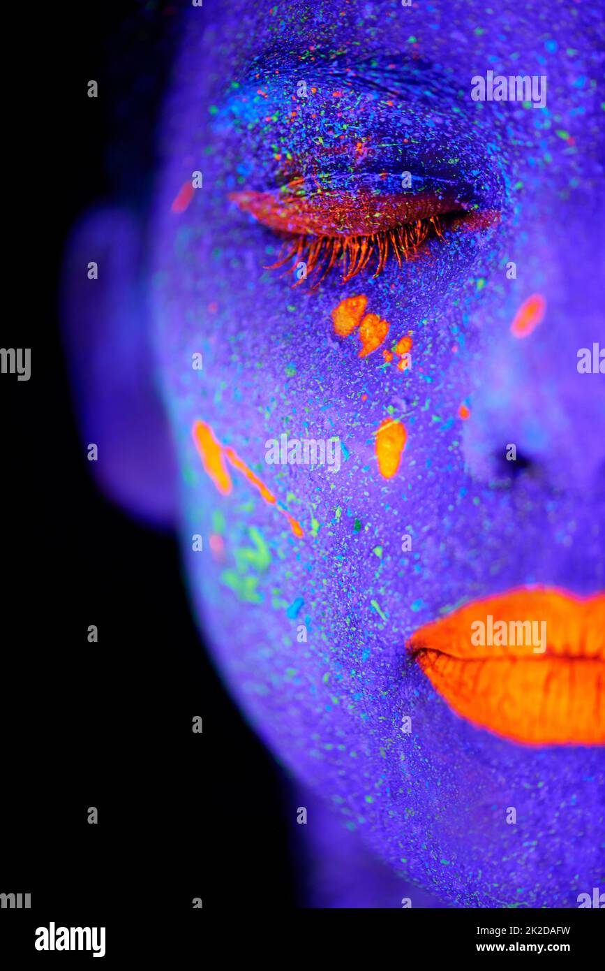 Imagine...a young woman posing with neon paint on her face. Stock Photo