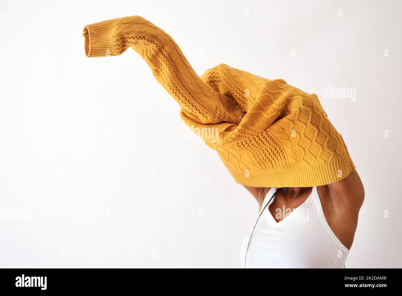 Its knitwear season. Studio shot of an unrecognizable woman getting dressed against a white background. Stock Photo
