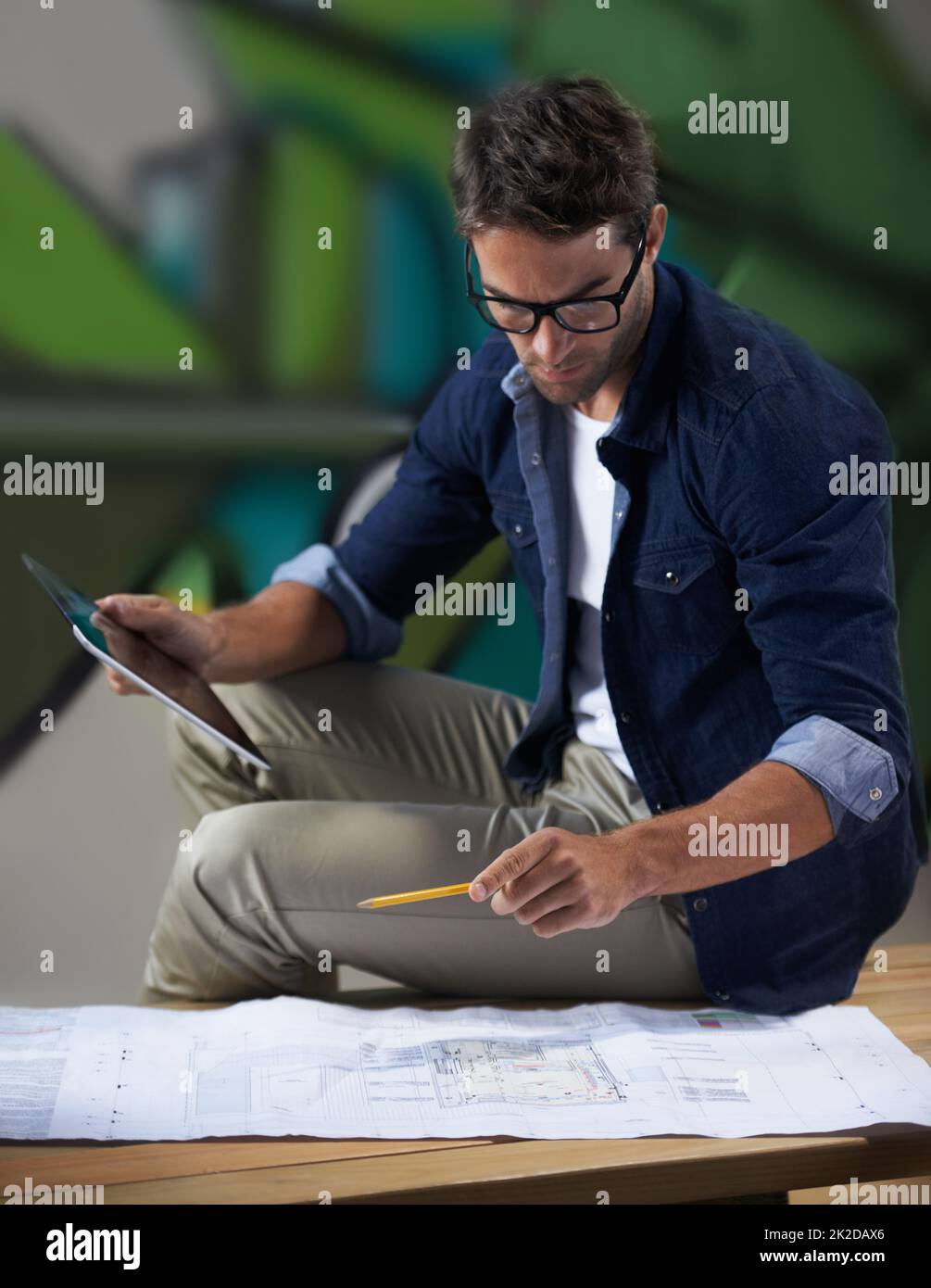 One final look at the plan before the presentation. Shot of a trendy male designer working on building plans at his desk. Stock Photo