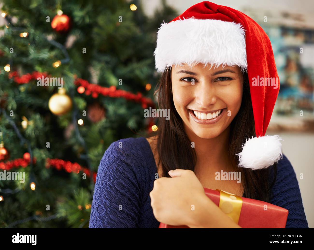 I need to open one now. Portrait of a young woman hold a Christmas gift. Stock Photo