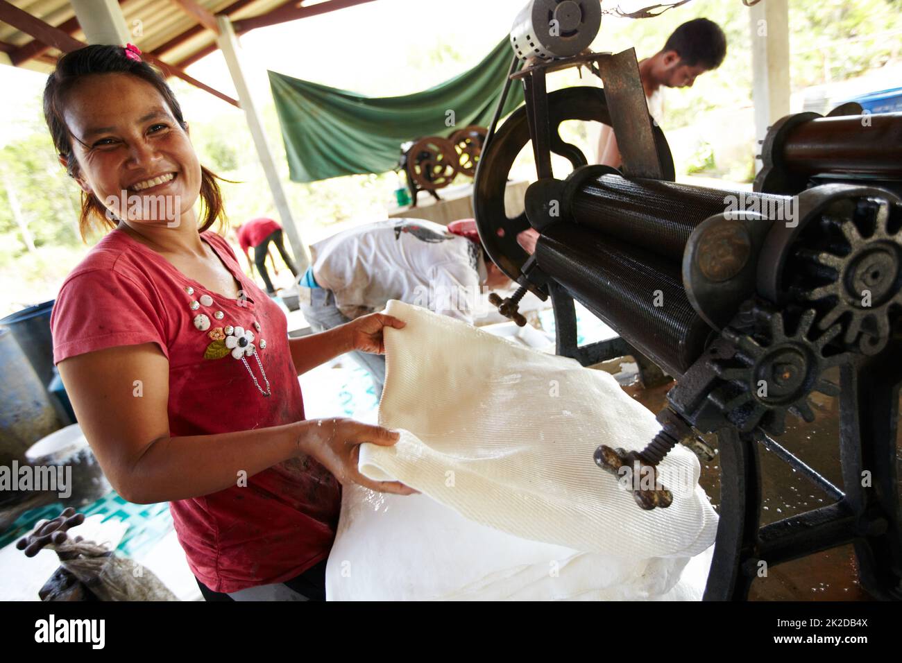 Job satisfaction. A Thai woman smiles while she rolls out rubber sheets. Stock Photo