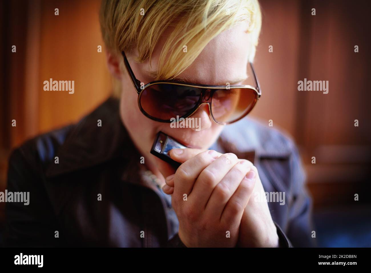 Making mellow music. Attractive young guy in urban wear playing the harmonica. Stock Photo