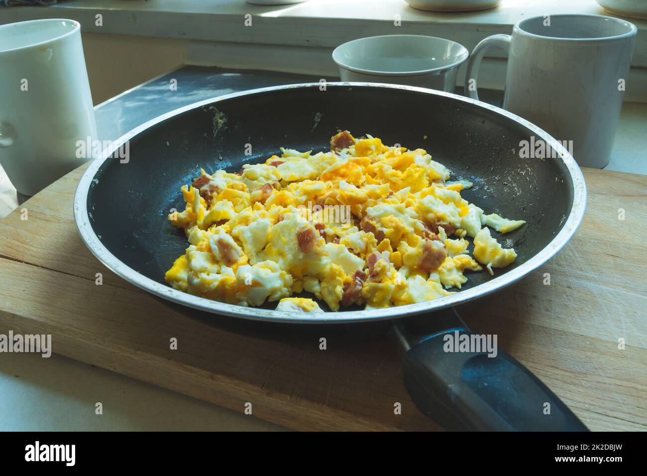 Fresh scrambled eggs with bacon in a pan Stock Photo