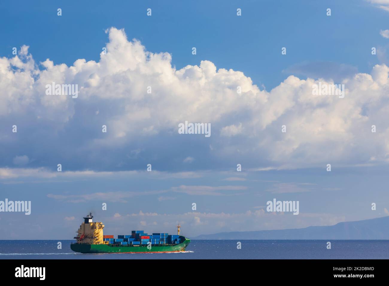 cargo ship nearby Capo Peloro Lighthouse in Punta del Faro on the Strait of Messina, most north eastern promontory of Sicily, Italy Stock Photo