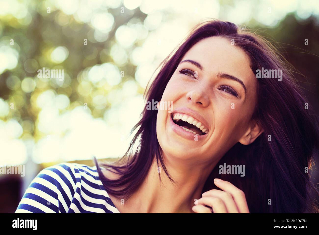 The picture of pure joy. Shot of a beautiful young woman laughing while standing outside. Stock Photo
