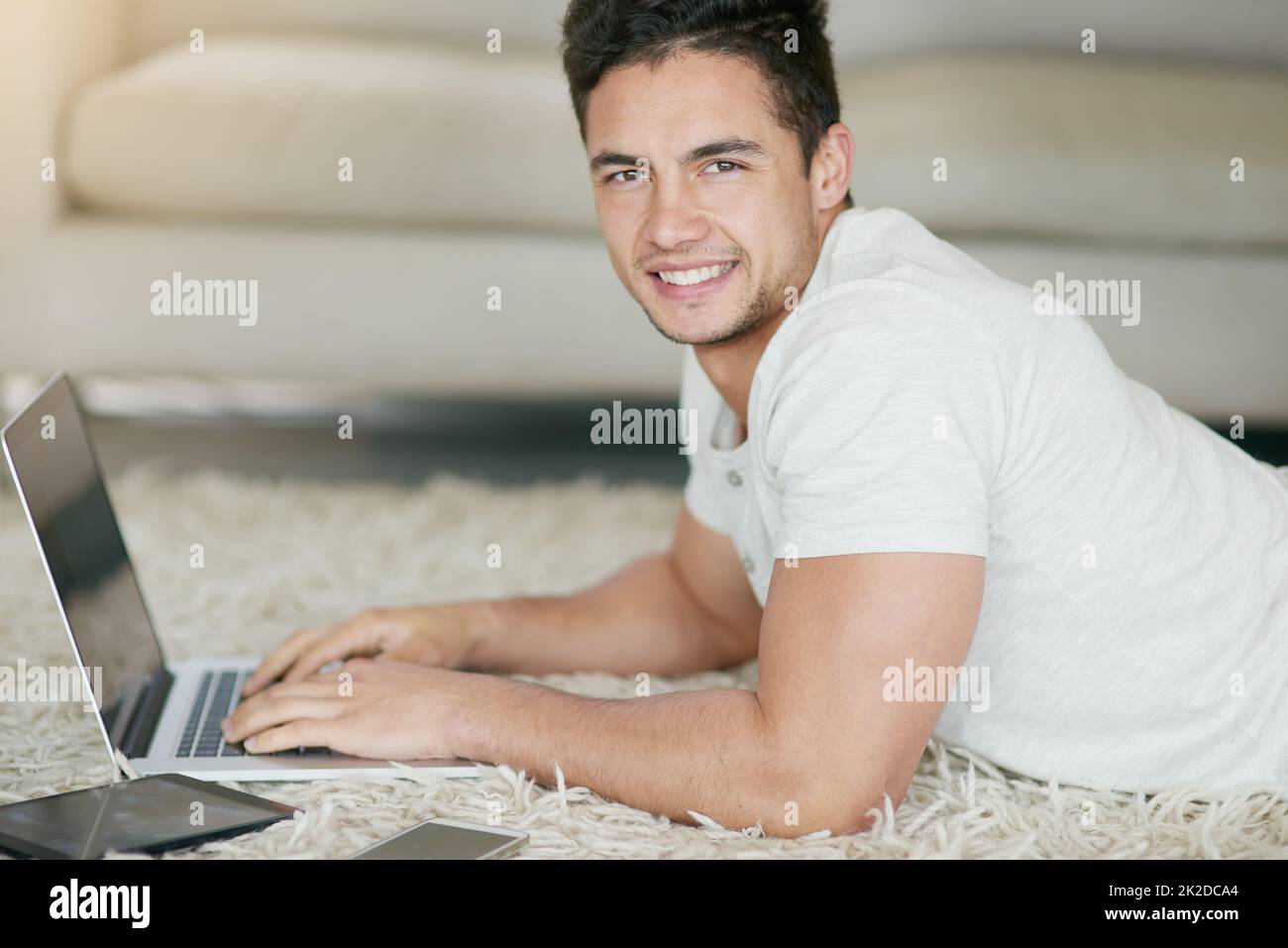The more wireless the more stressless. Portrait of a relaxed young man using a laptop on the floor at home. Stock Photo