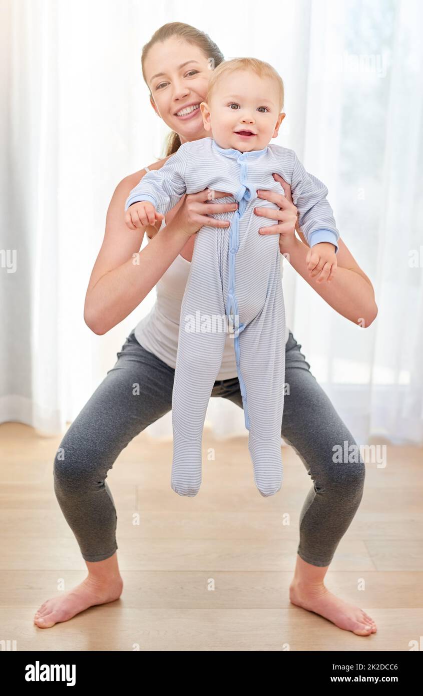 Its good for you and fun for your baby. Shot of a young woman working out while spending time with her baby boy. Stock Photo