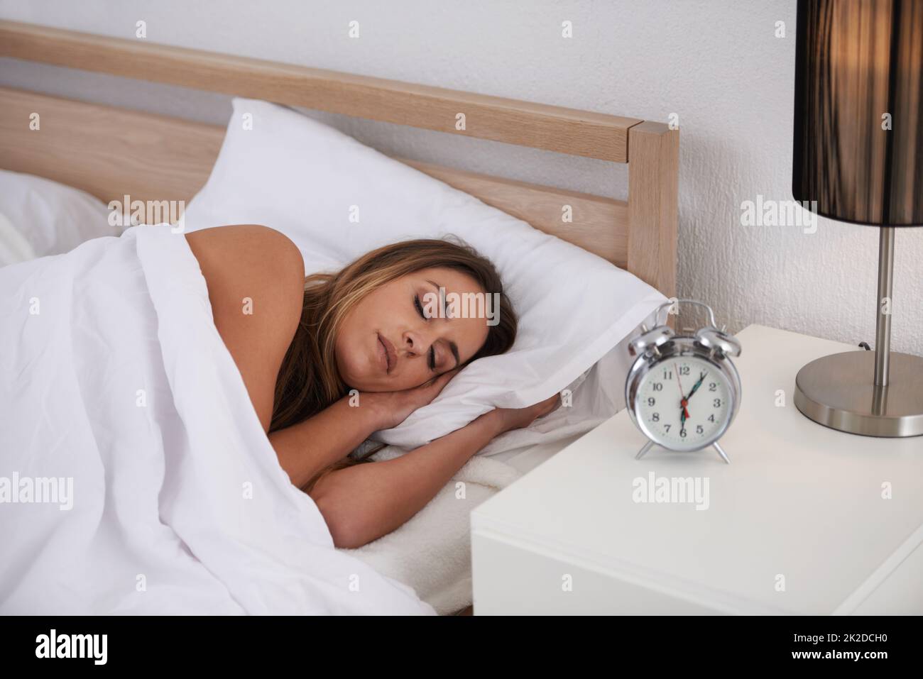 The alarm will go off soon.... Shot of a beautiful young woman sleeping in her bed. Stock Photo